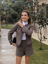 a lady in retro style brown tweed jacket with brown shorts
